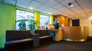 A reception area with a wooden reception desk, a brown leather bench, and a red carpet.