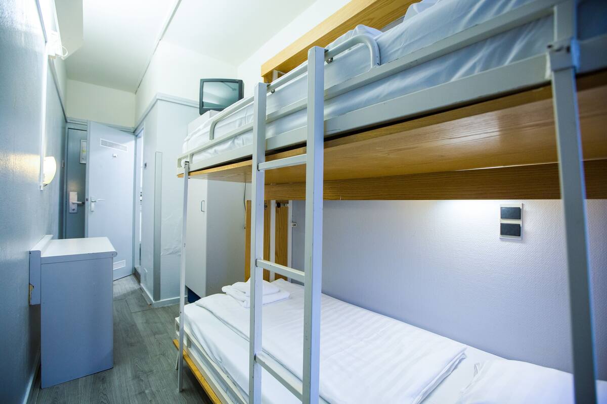A bunk bed room with a desk and a television.