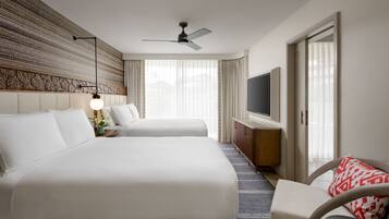 A hotel room with two beds, a TV, a ceiling fan, and a large window with curtains.