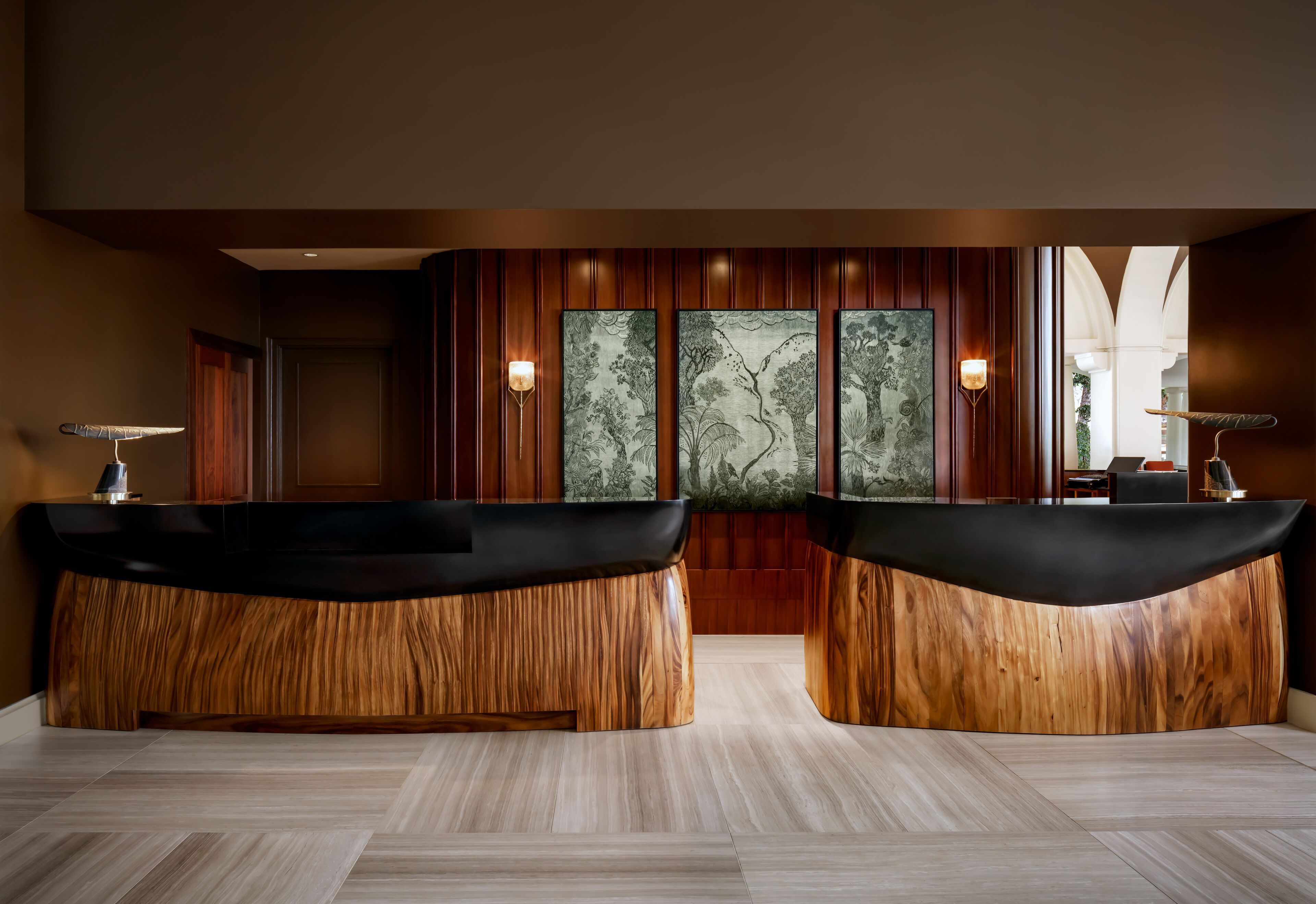 A reception area with two wooden reception desks, a wall-mounted artwork, and a wooden panel backdrop.