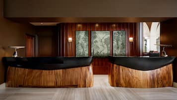 A reception area with two wooden reception desks, a wall-mounted artwork, and a wooden panel backdrop.