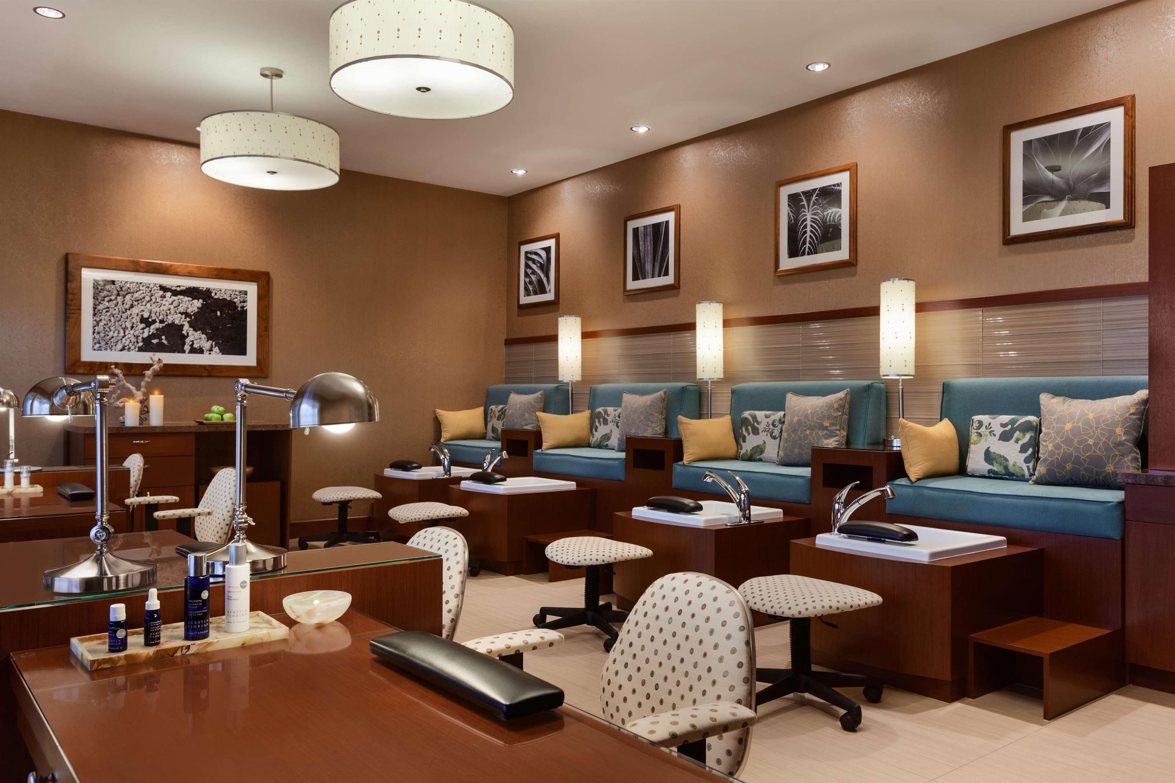A well-lit, modern hotel room with a large bed, bedside tables, a desk with a computer, and a seating area with a sofa and chairs.