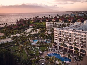 Un resort con una piscina grande, varias edificaciones y vista al océano.