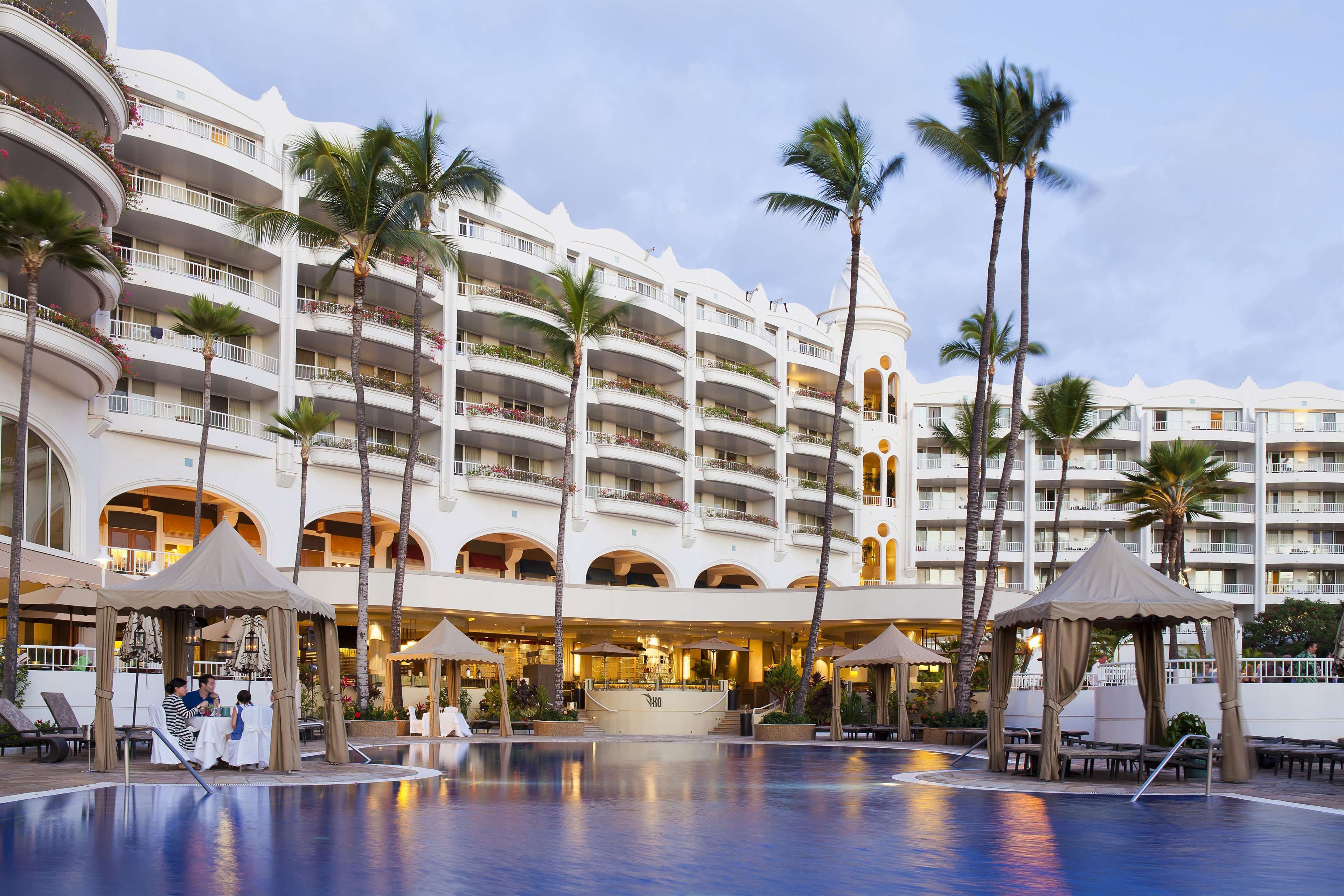 Un hotel con varios balcones, piscina y zonas de estar al aire libre.
