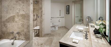 A modern bathroom with a bathtub, shower, and two sinks.