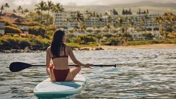 A person sitting on a paddleboard in a body of water with a resort in the background.