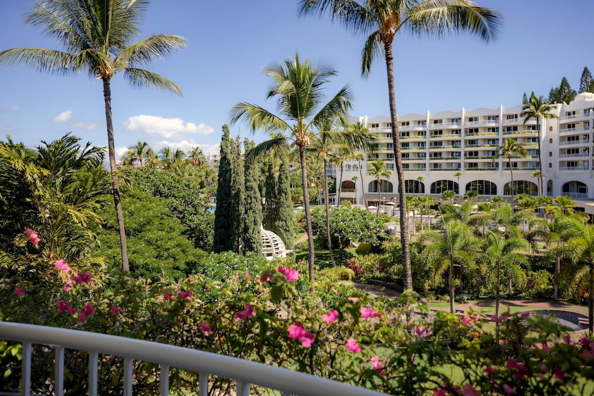 A resort with a large building surrounded by lush greenery and palm trees.