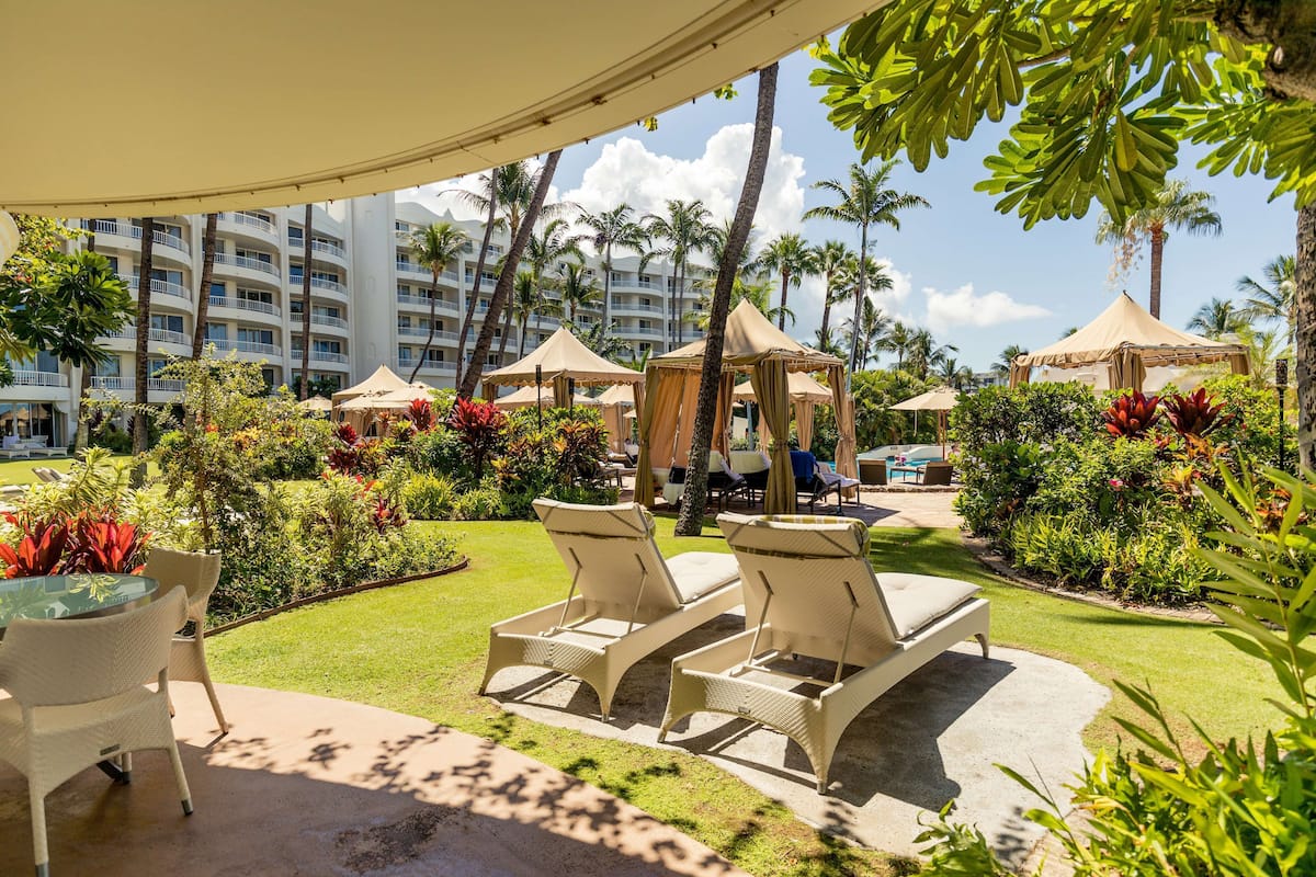 A resort courtyard with lounge chairs, a table, and a tent.