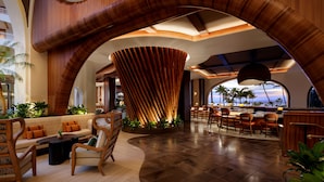A spacious lobby with a curved wooden arch, seating areas, and a bar. - Fairmont Kea Lani Maui (Kihei)
