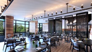 A modern restaurant with a mix of round and rectangular tables, some with napkins and glasses. Large windows offer views of the outdoors. - Amway Grand Plaza, Curio Collection by Hilton (Grand Rapids)