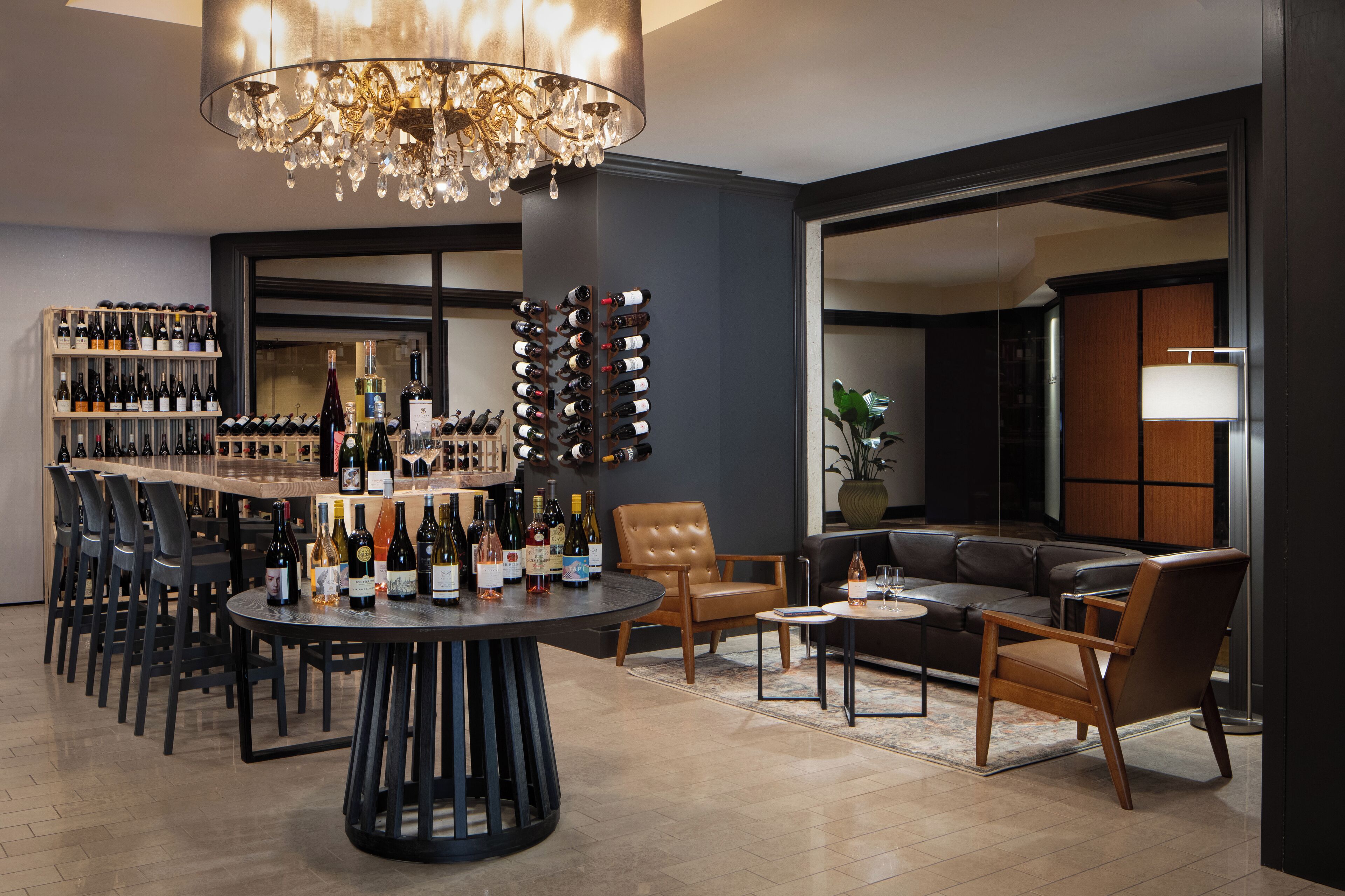 Ein modernes Interieur mit Bar, Weinkühlschränken, Ledersitzmöbeln und einer Kristallleuchtre.