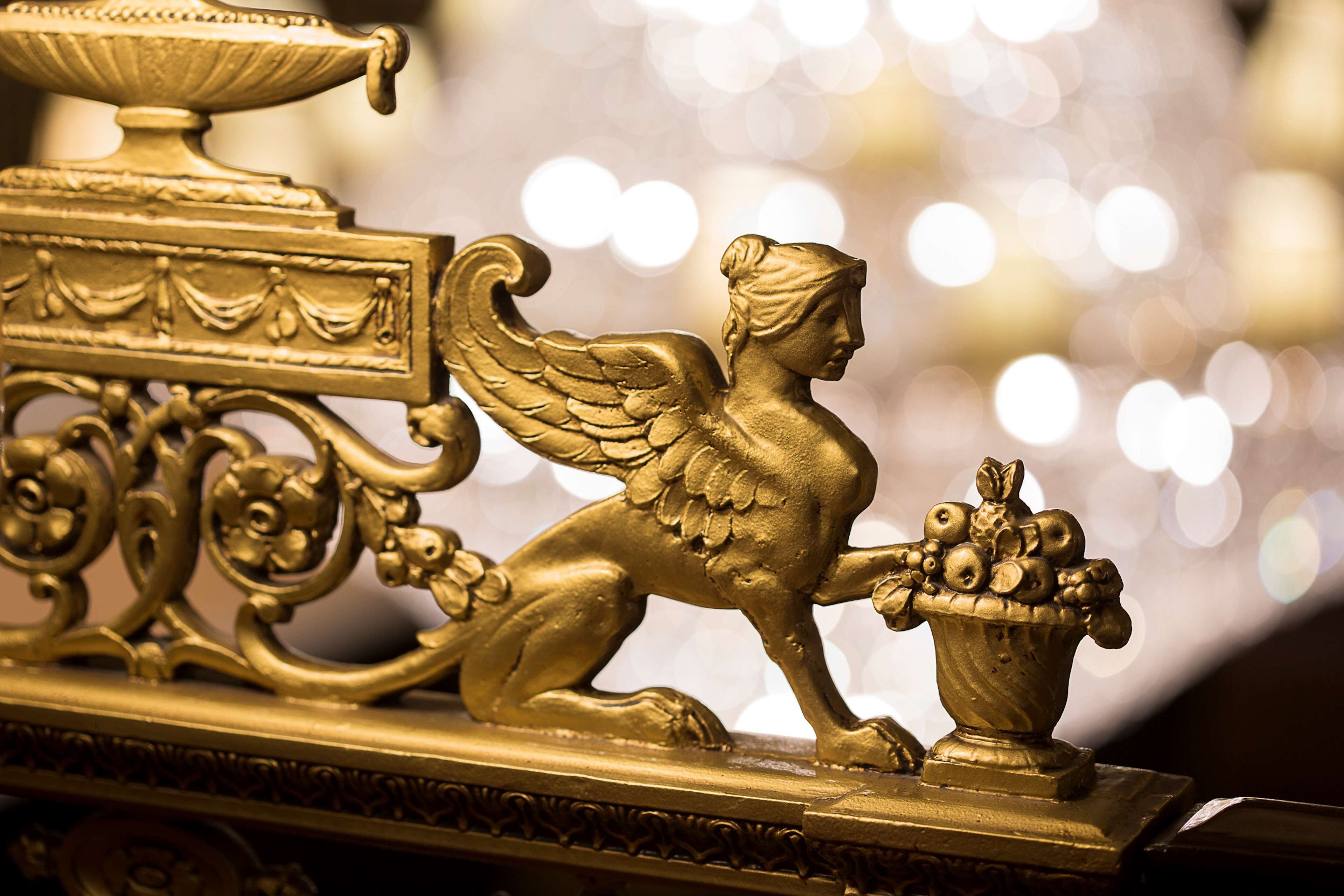 A golden ornate metal sculpture with a winged figure holding a basket.