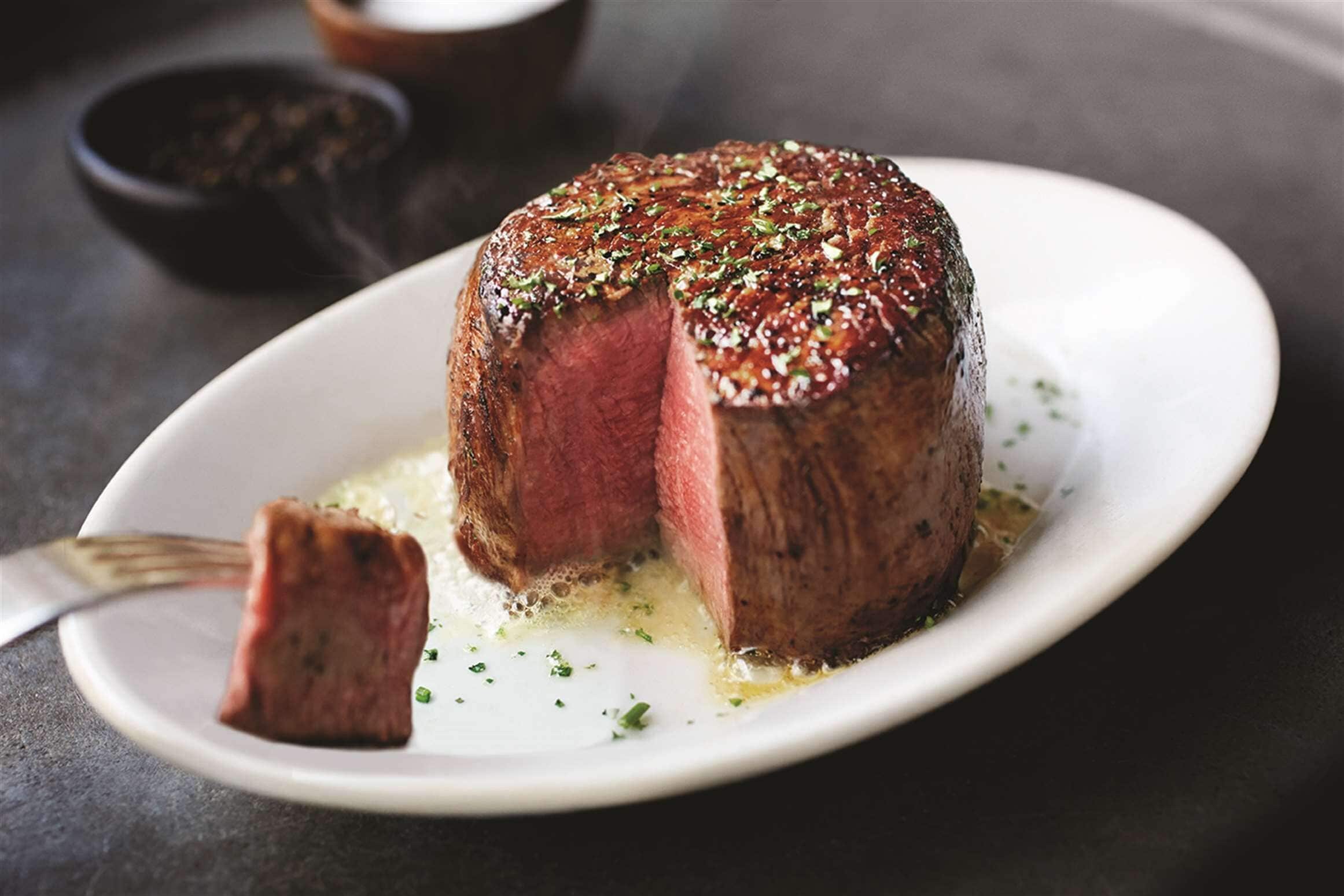 A steak with a crust on a white plate.