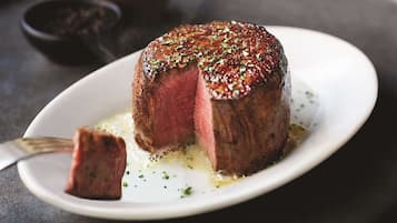 A steak with a crust on a white plate.