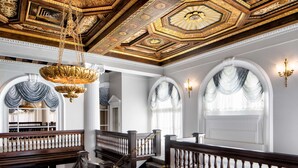 A grand staircase with ornate railings, a richly decorated ceiling, and large windows with draped curtains. - Amway Grand Plaza, Curio Collection by Hilton (Grand Rapids)