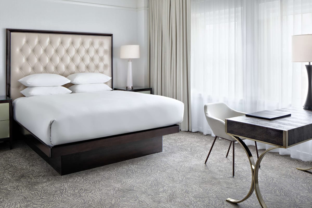 Ein Hotelzimmer mit einem großen Bett, einem Schreibtisch und einem Sessel.