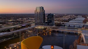 A high-rise hotel room with a balcony overlooking a cityscape, a river, and a bridge. - Amway Grand Plaza, Curio Collection by Hilton (Grand Rapids)