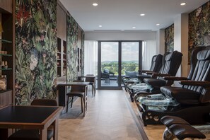 A spa area with massage chairs, a reception desk, and a view of the city through large windows.
