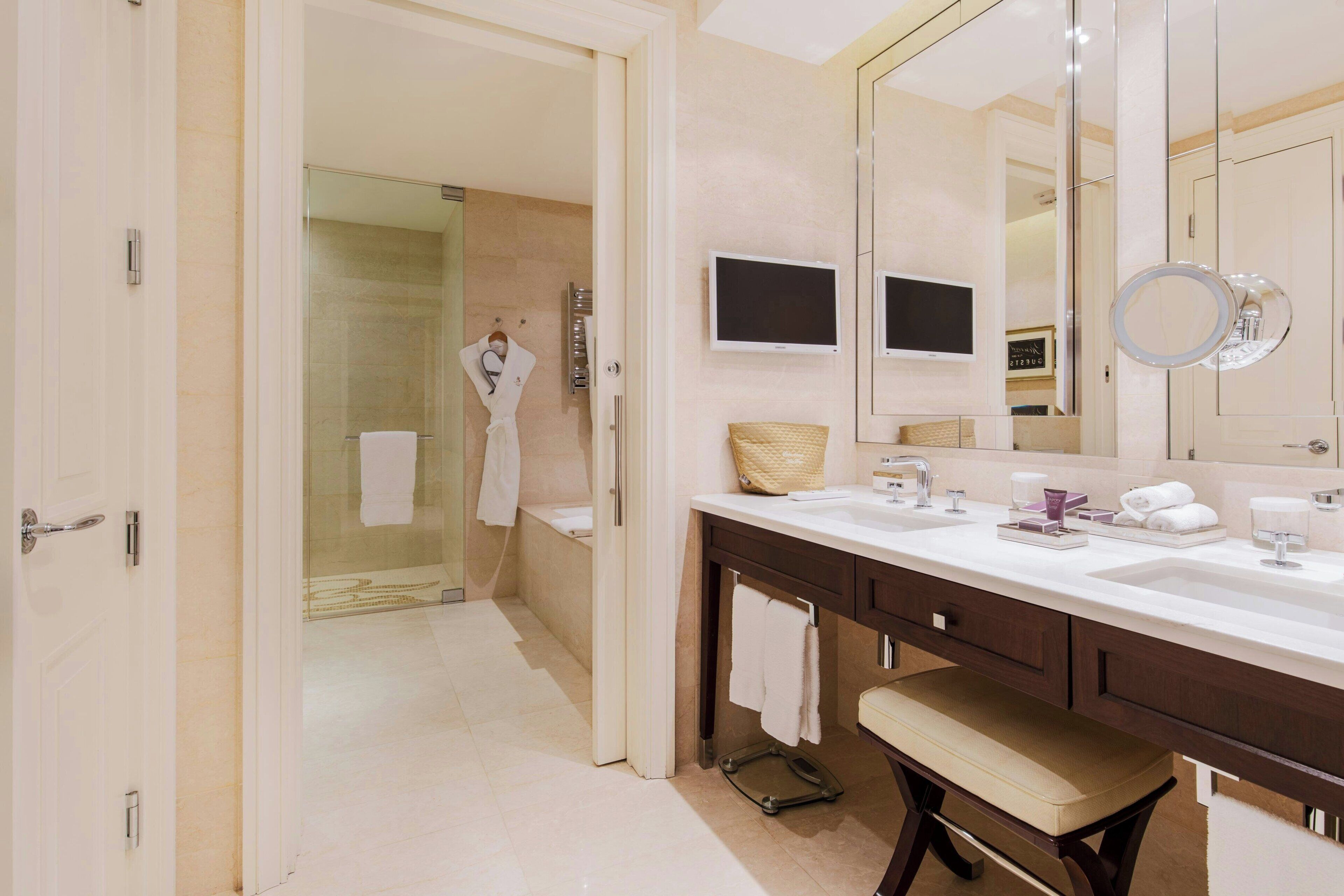 Un baño moderno con un espejo grande, tocador y zona de ducha.
