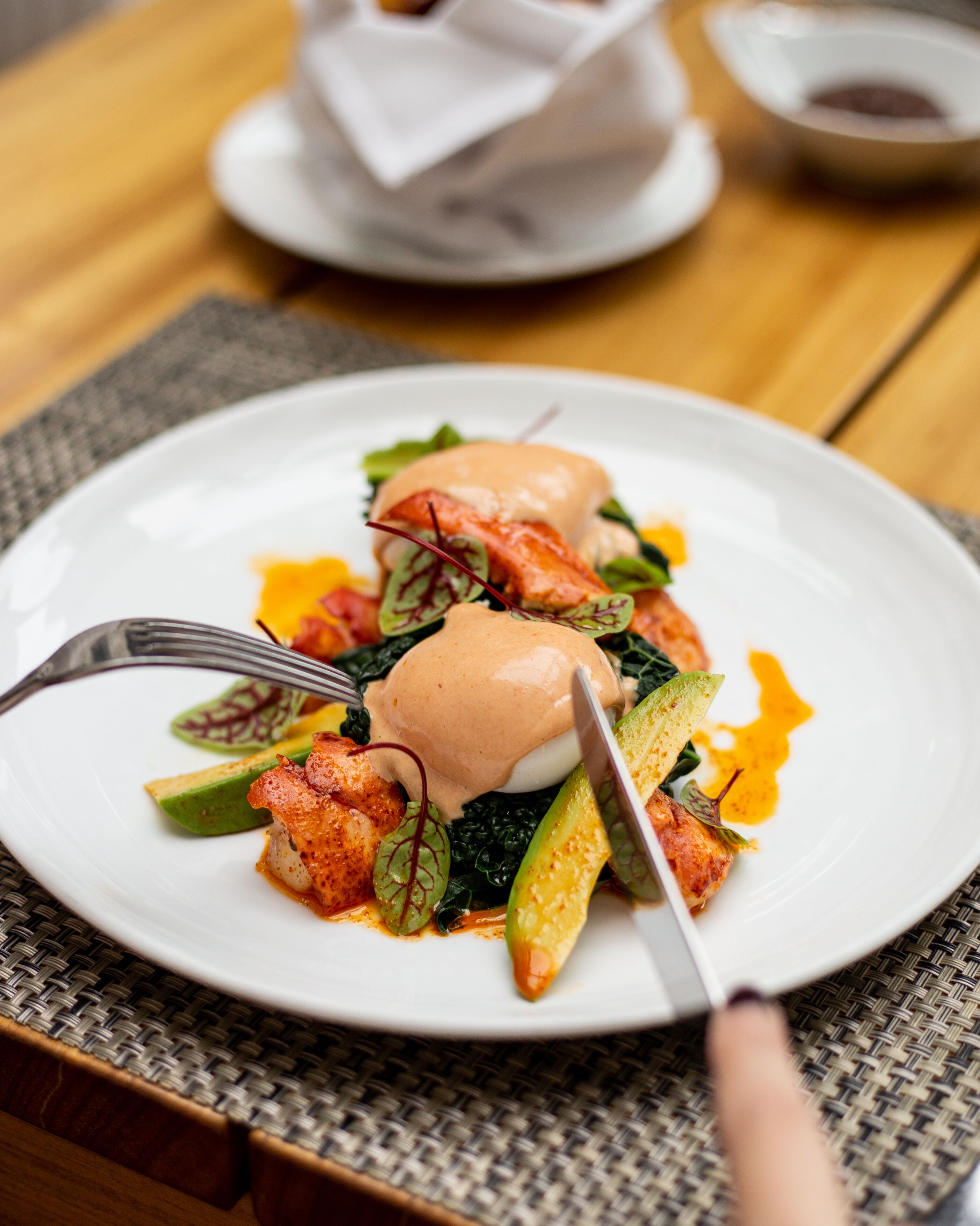 Une assiette de nourriture comprenant un œuf poché, des légumes verts et une sauce.