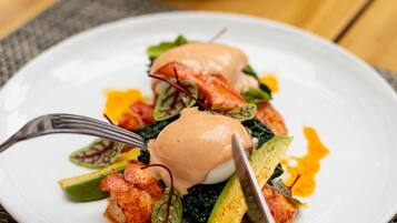 Une assiette de nourriture comprenant un œuf poché, des légumes verts et une sauce.