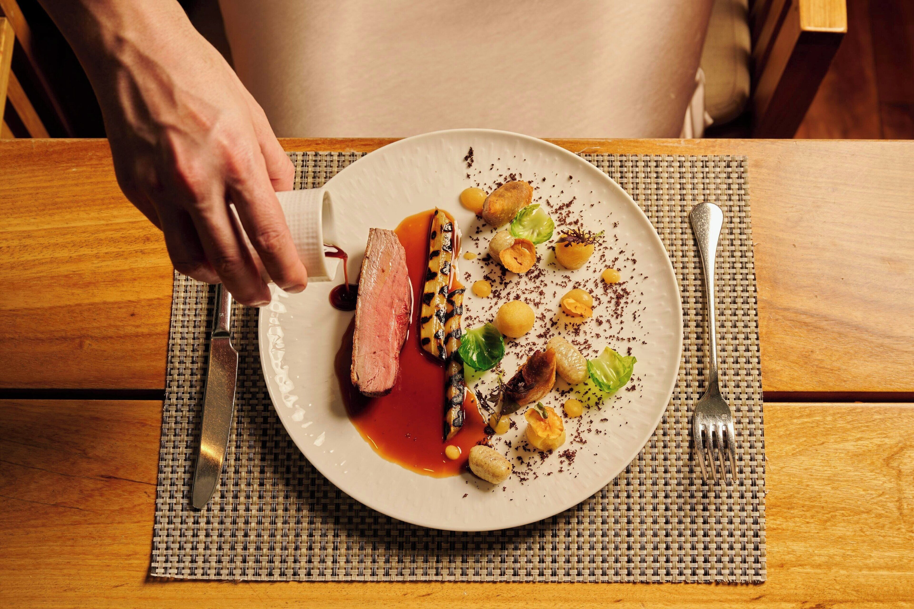 A plate of food with a knife and fork on a woven placemat.