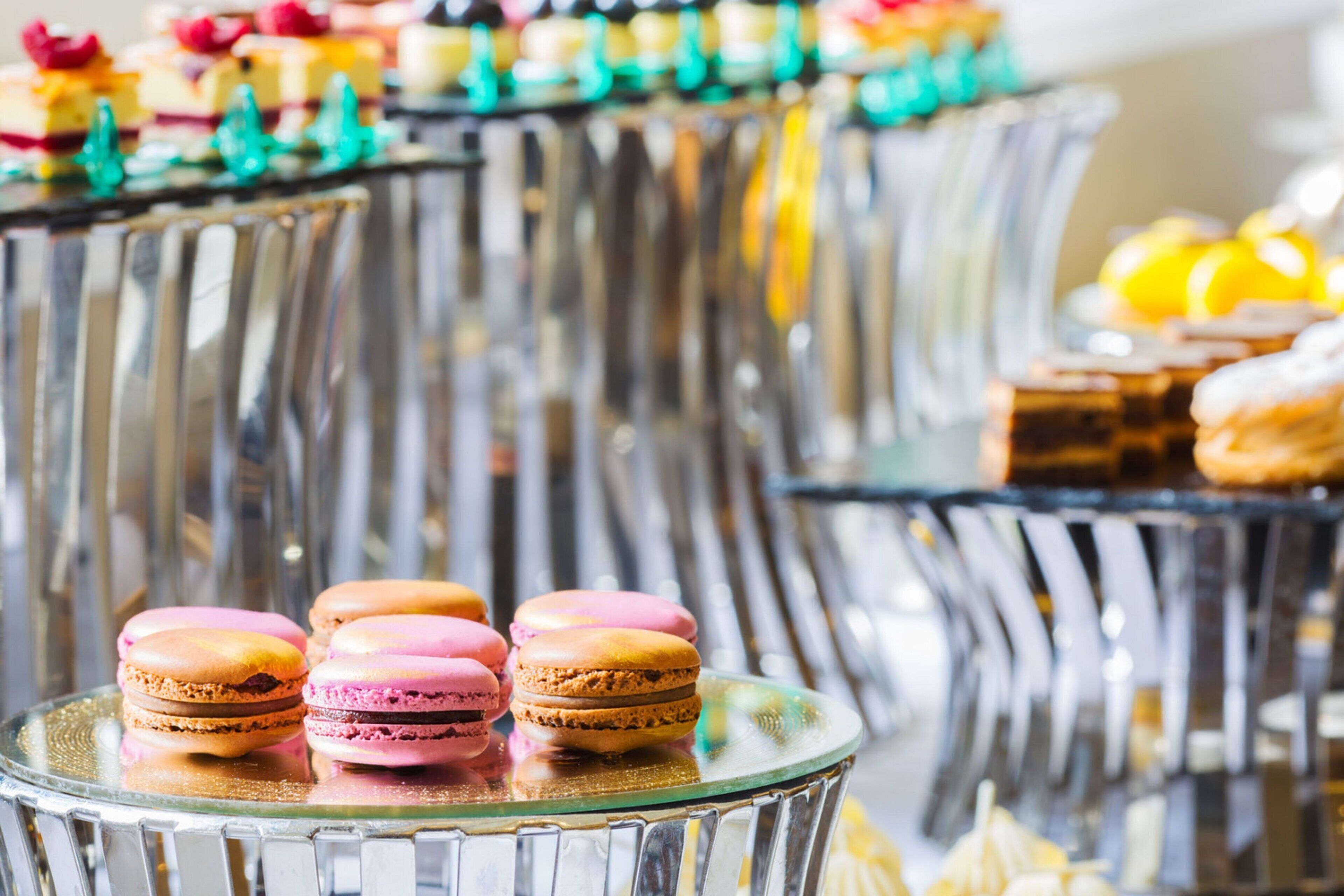 A dessert display with macarons and other pastries on glass stands.