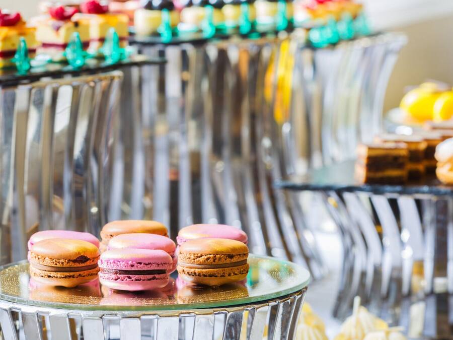 A dessert display with macarons and other pastries on glass stands.