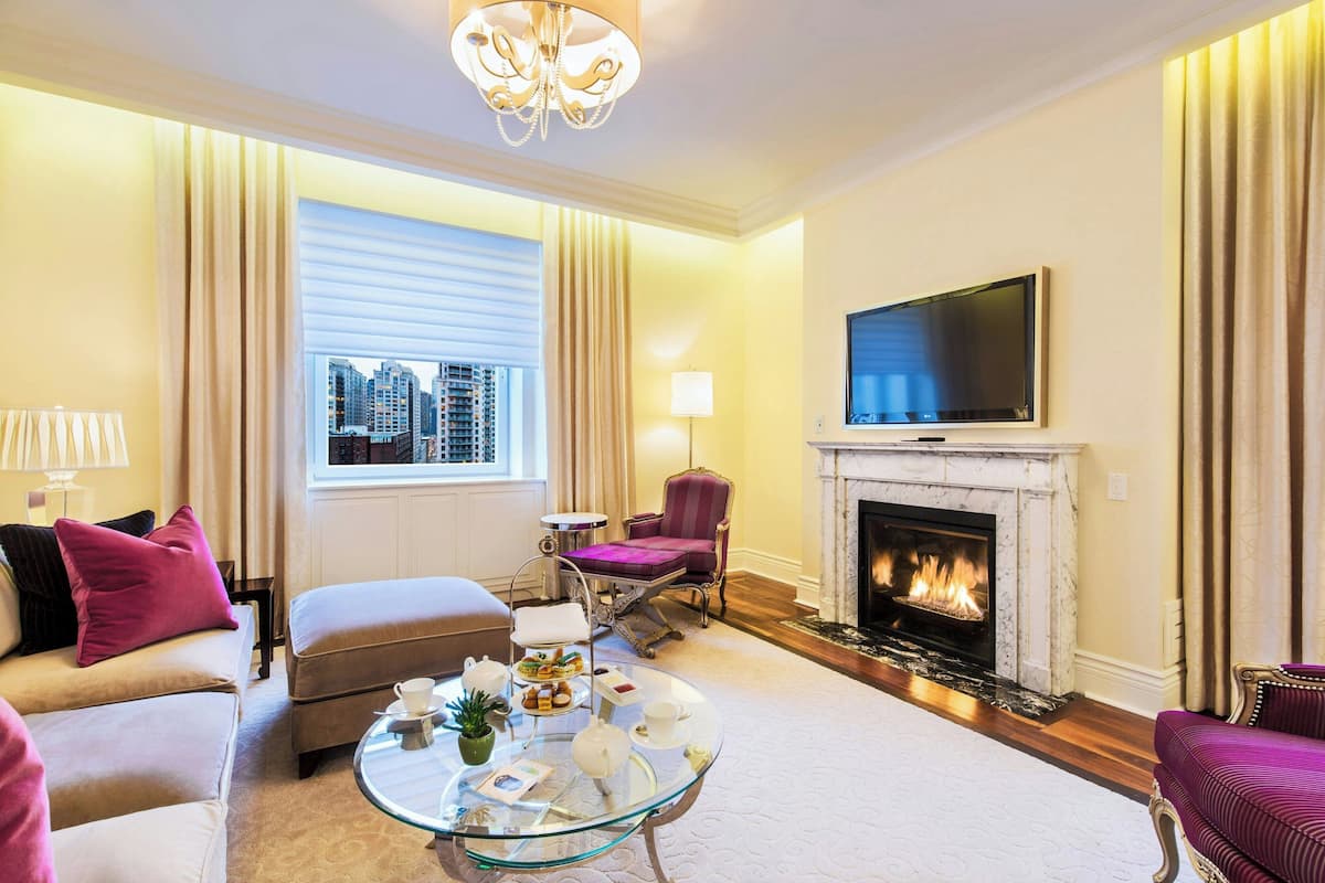 A spacious living room with a fireplace, a television mounted above it, and a comfortable seating area with a sofa and armchairs.