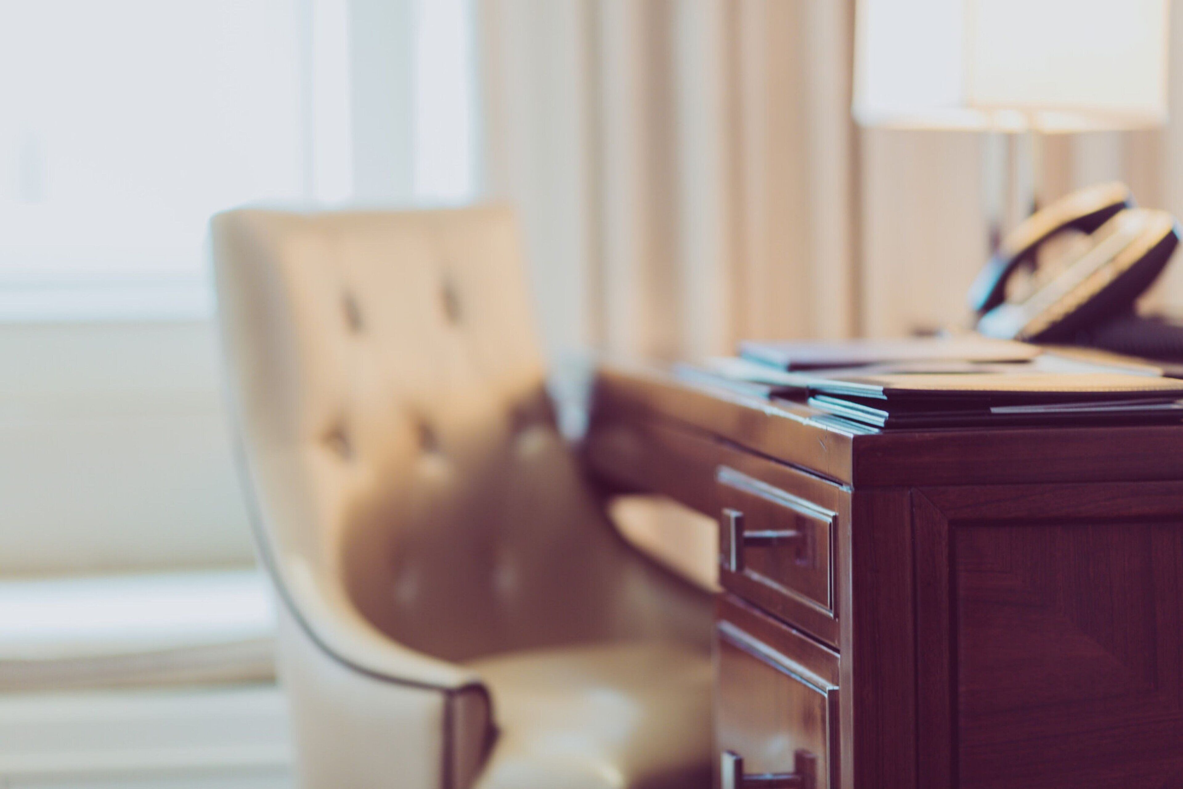 Een houten bureau met lades, een lamp en een telefoon.