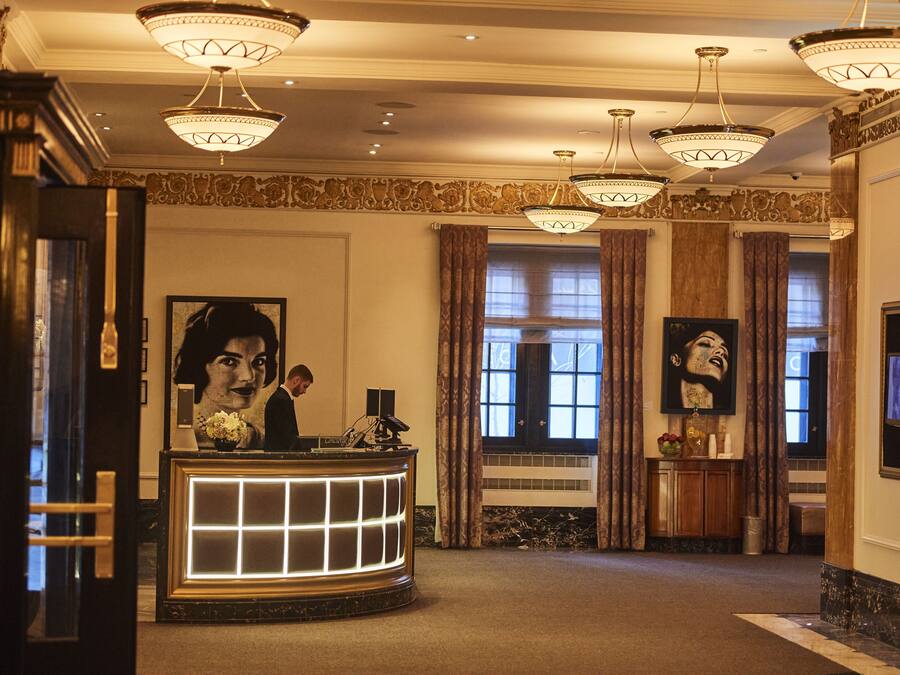 Un hall d’entrée avec un comptoir de réception, des lustres et des œuvres d’art encadrées accrochées aux murs.