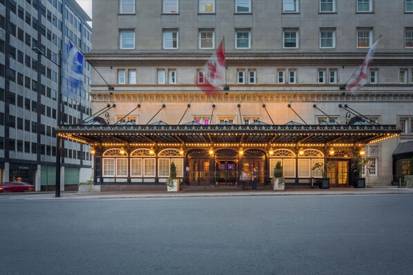 A grand hotel entrance with a covered entrance, large windows, and flags.