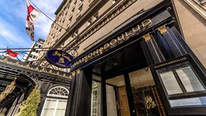 Une façade d’immeuble avec une enseigne indiquant « MAISON BOULUD » et un drapeau au-dessus.