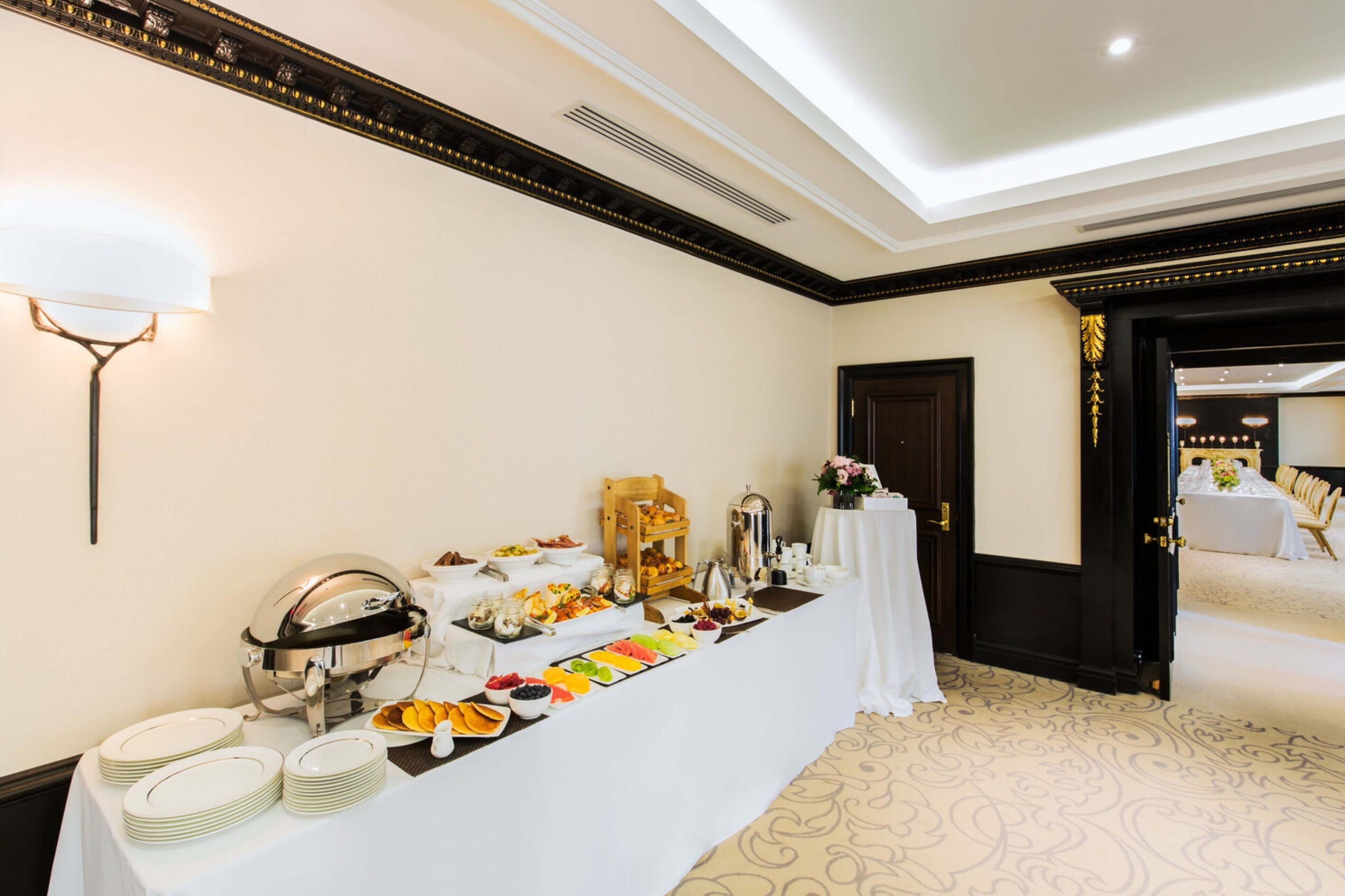A buffet setup with various food items and a silver serving dish.