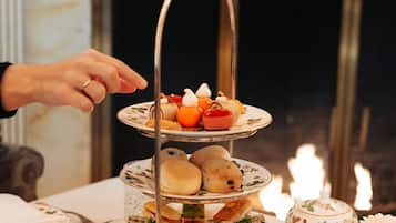 A tiered dessert stand with various pastries and a teapot on a table.