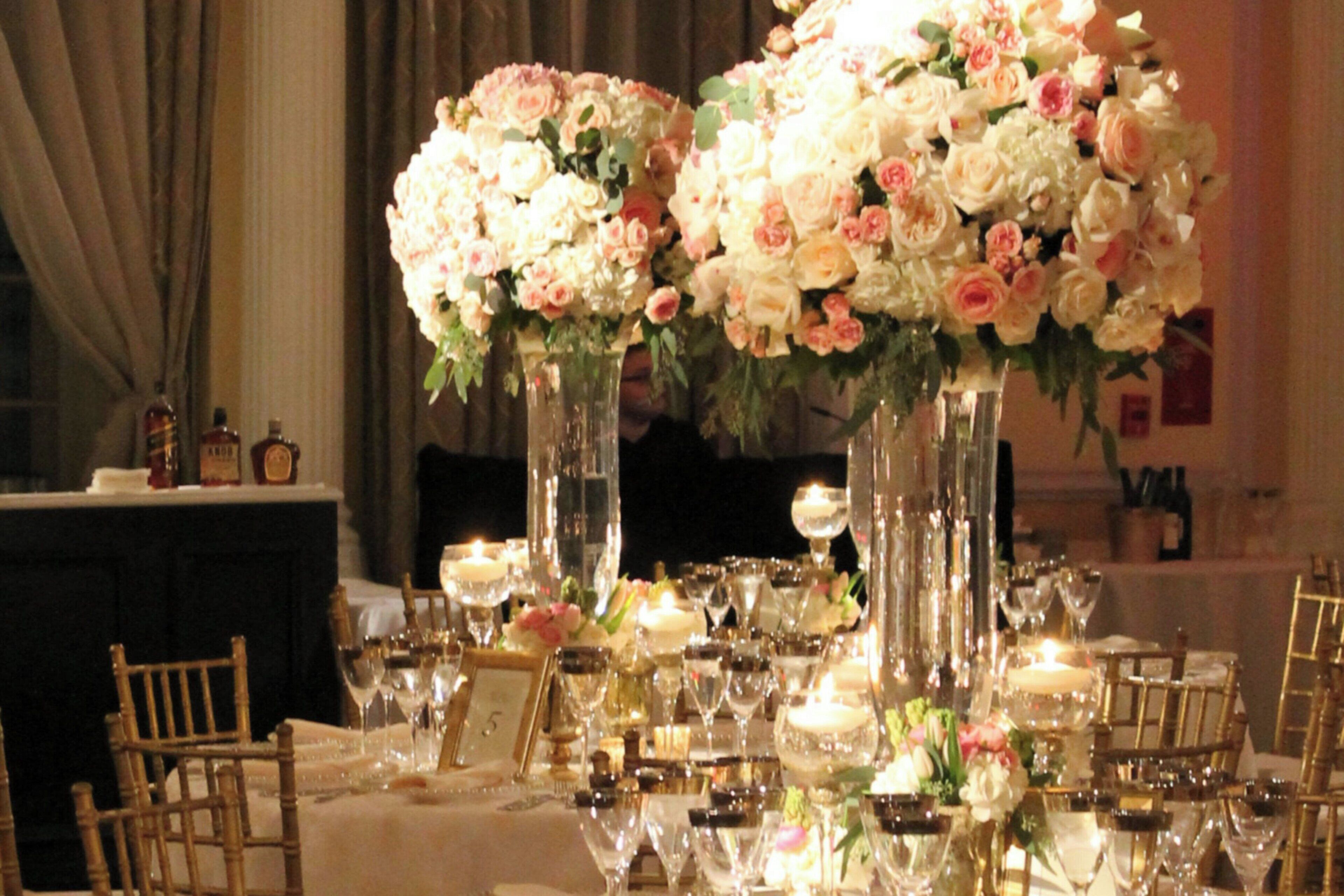 A table set for a formal event with tall vases of flowers, wine glasses, and candles.