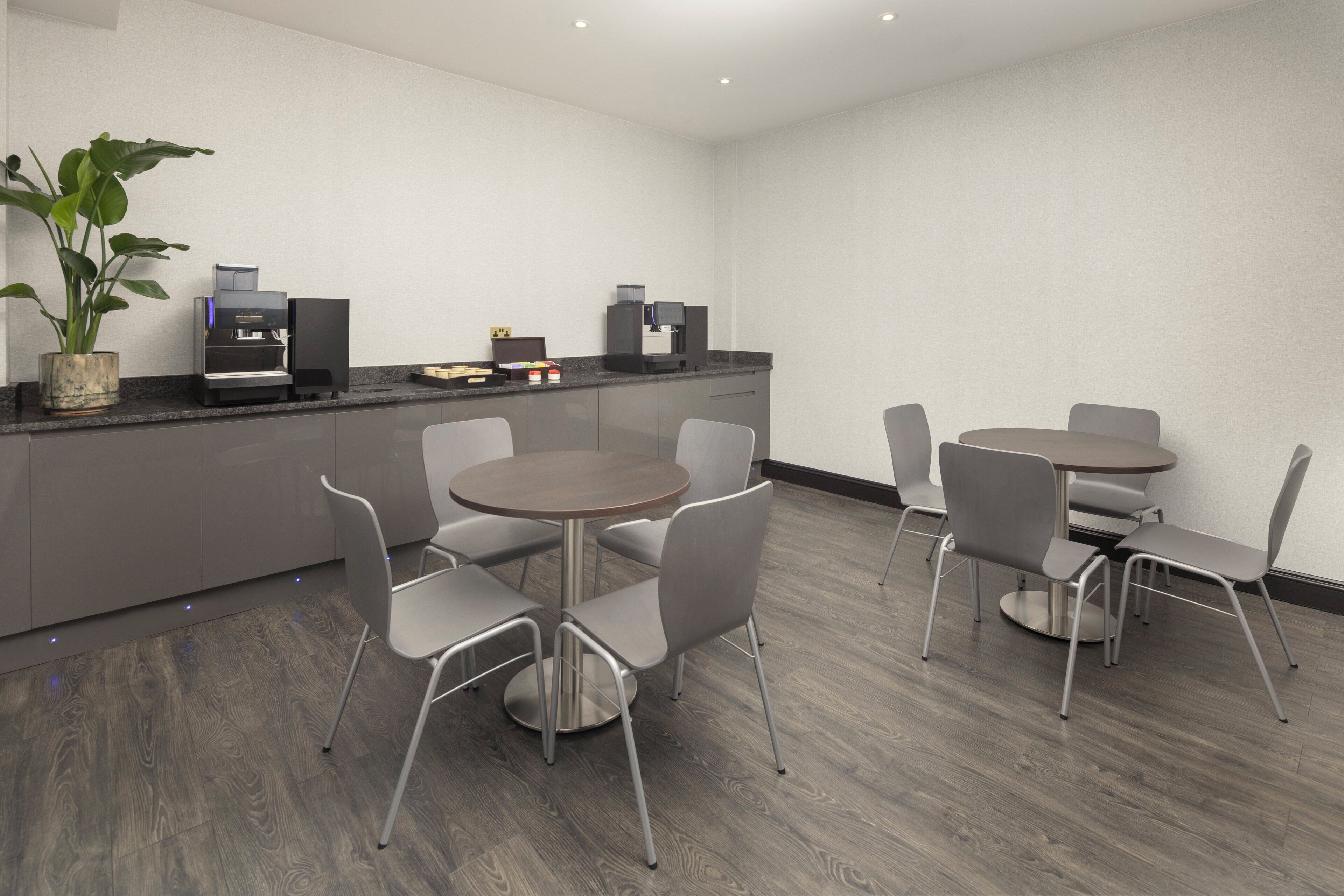 A modern kitchen with built-in appliances, grey cabinets, and a round dining table with chairs.