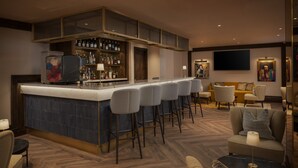 Eine Bar mit einer hohen Theke, mehreren Hockern und einer Sitzecke mit Sofas und Sesseln.