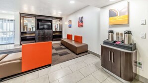 A modern hotel room with a sofa, a TV, a cabinet with coffee makers, and a wall-mounted artwork. - Motel 6 Lewisville, TX - Medical City (Lewisville)