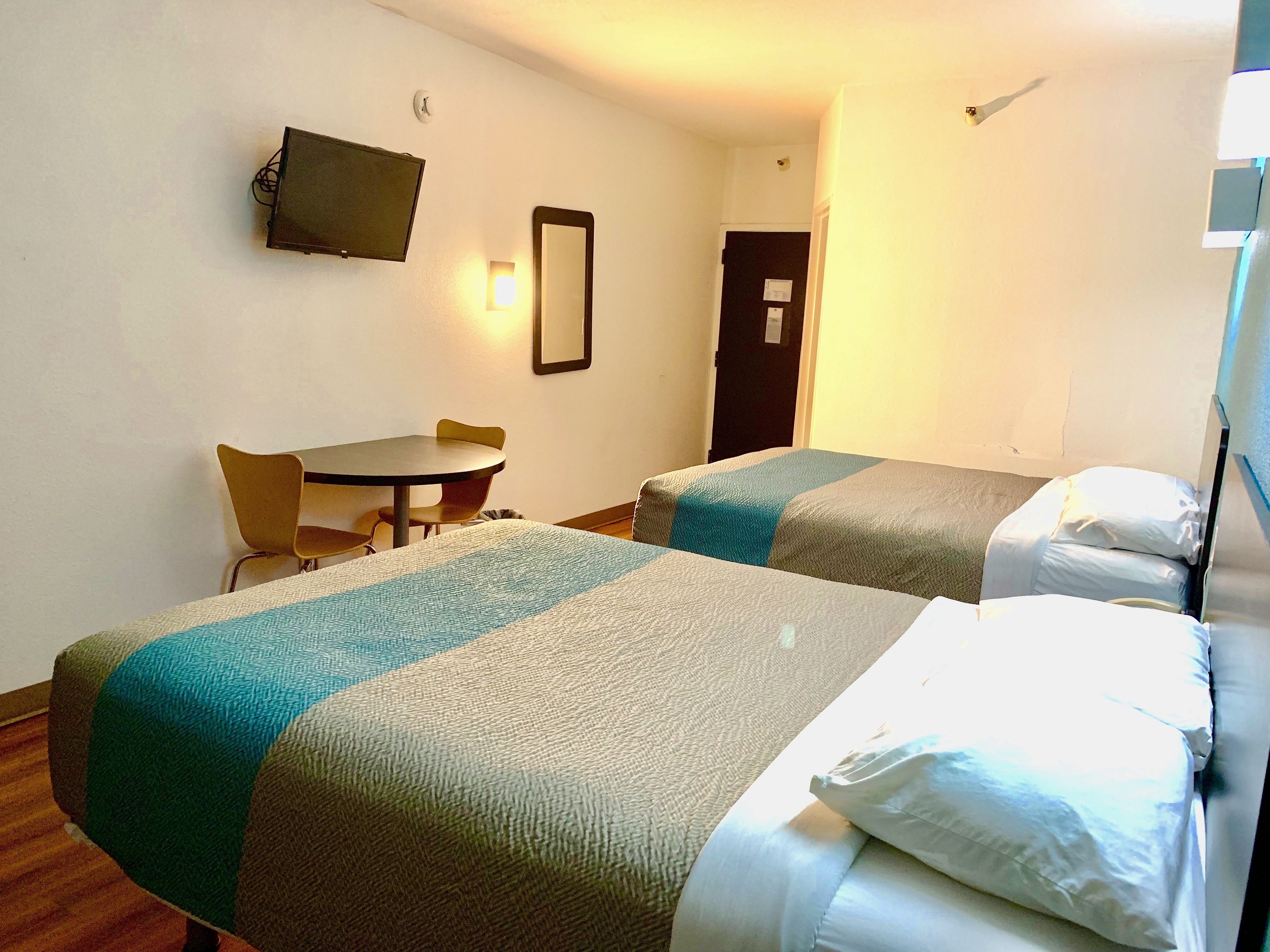 A hotel room with two beds, a desk, and a chair.