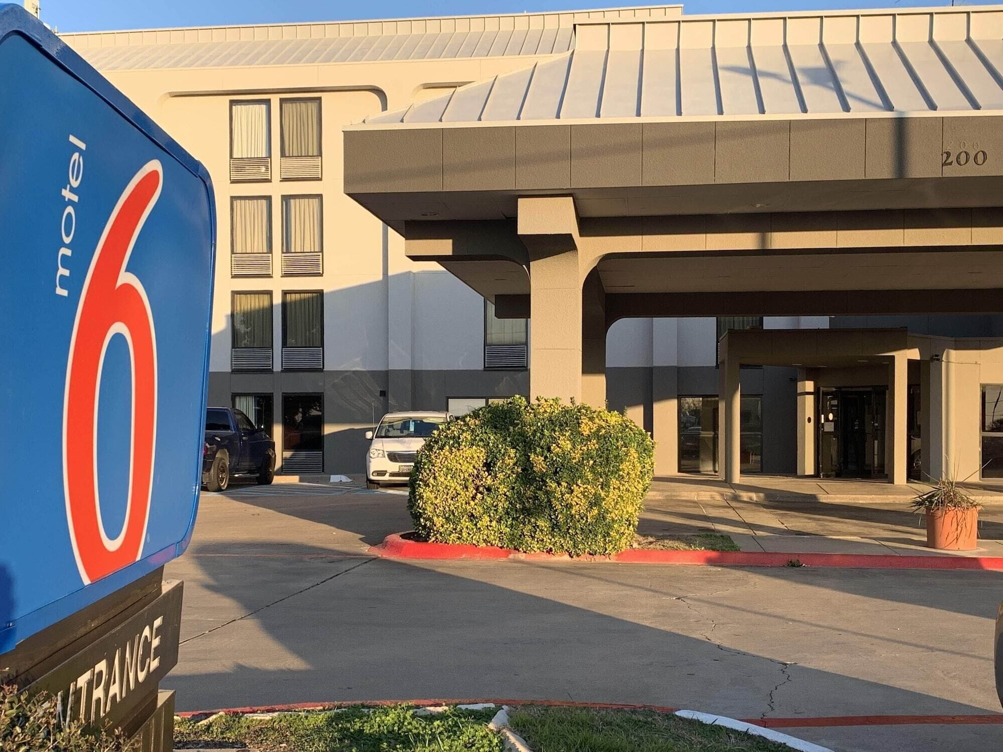 Un motel con un letrero grande, un estacionamiento y un edificio de techo plano.