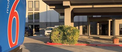 Un motel con un letrero grande, un estacionamiento y un edificio de techo plano.
