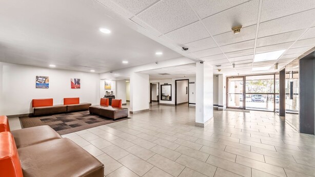 A spacious lobby with a seating area, a reception desk, and a view of the outside. - Motel 6 Lewisville, TX - Medical City (Lewisville)