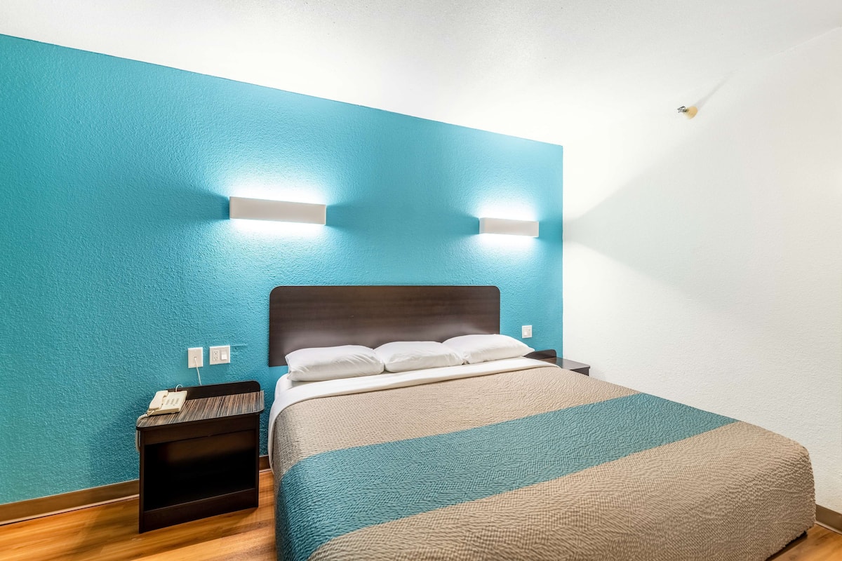 Ein Hotelzimmer mit Bett, Nachttisch und einer Wandleuchte.
