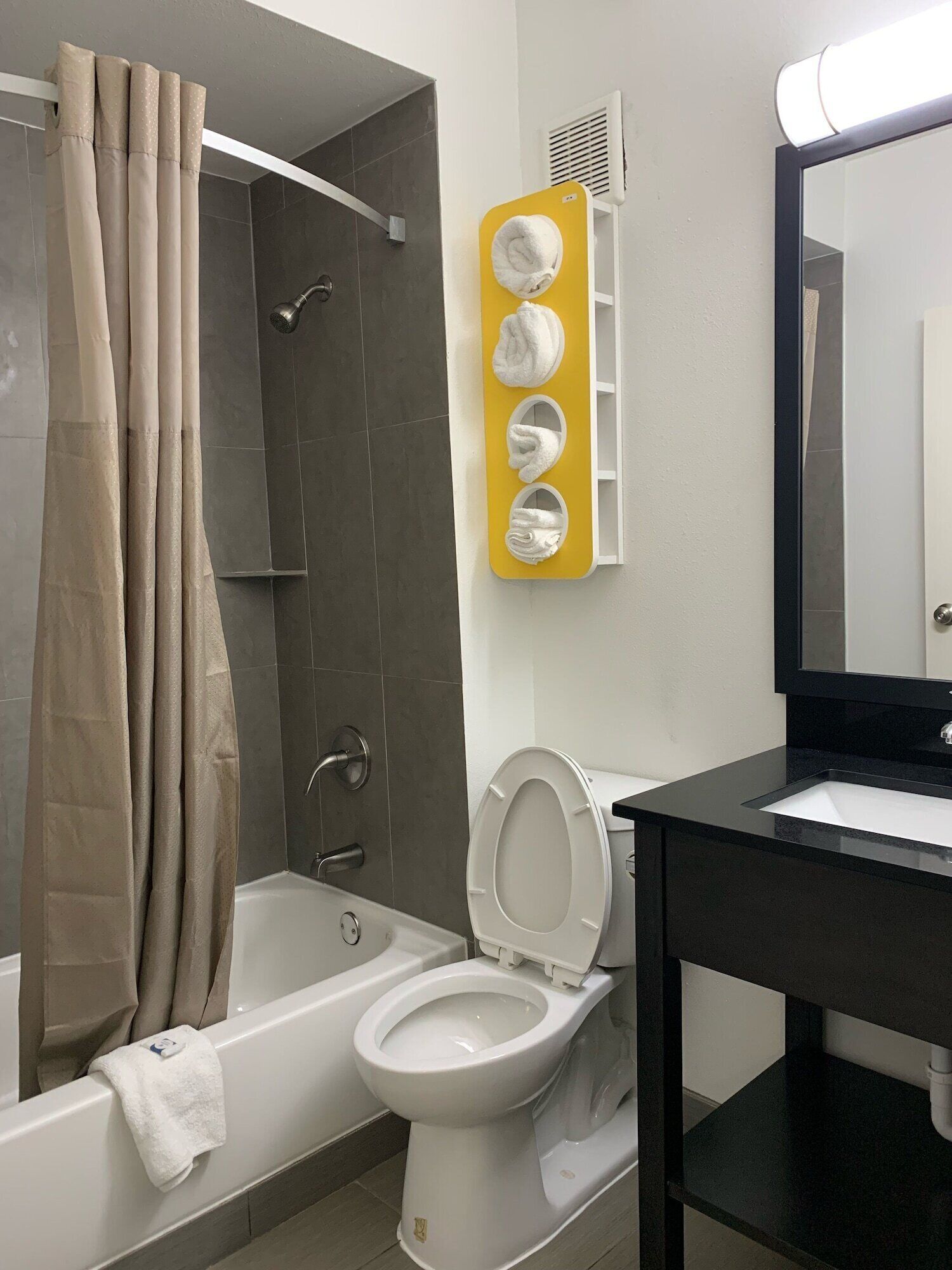 A bathroom with a bathtub, toilet, and a towel rack with multiple towels.