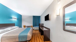 A hotel room with a bed, a desk, a chair, a television, and a window with curtains. - Motel 6 Lewisville, TX - Medical City (Lewisville)