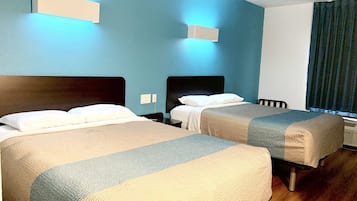 Habitación de hotel con dos camas, piso de madera y una ventana con cortinas.
