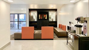 A modern lounge area with seating, a television, and a coffee station. - Motel 6 Lewisville, TX - Medical City (Lewisville)