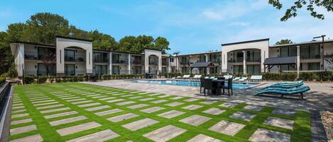 Un hôtel moderne doté d’une piscine, d’un espace extérieur aménagé et d’une pelouse bien entretenue.