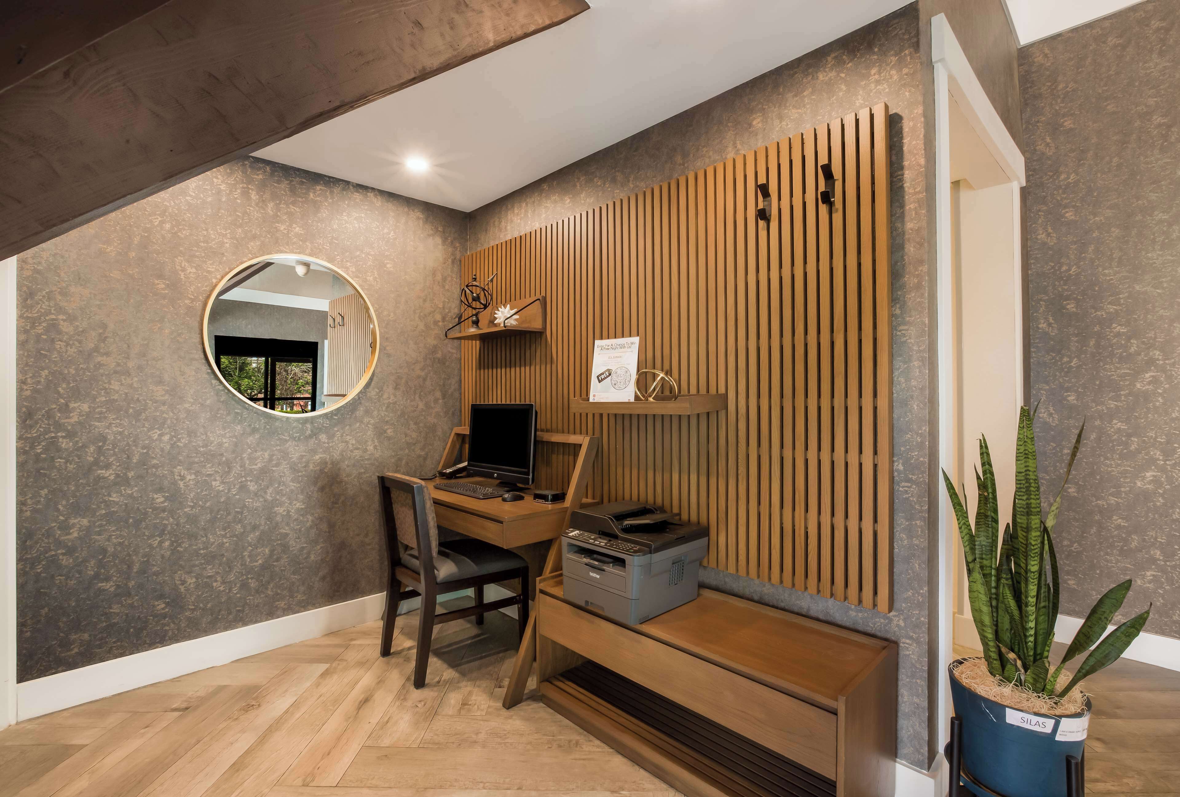 A modern office space with a wooden desk, computer, printer, and a potted plant.